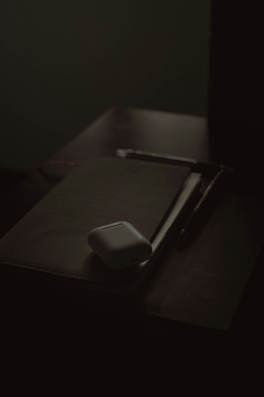Detective notebook with handwritten notes, magnifying glass and old photographs on a wooden desk
